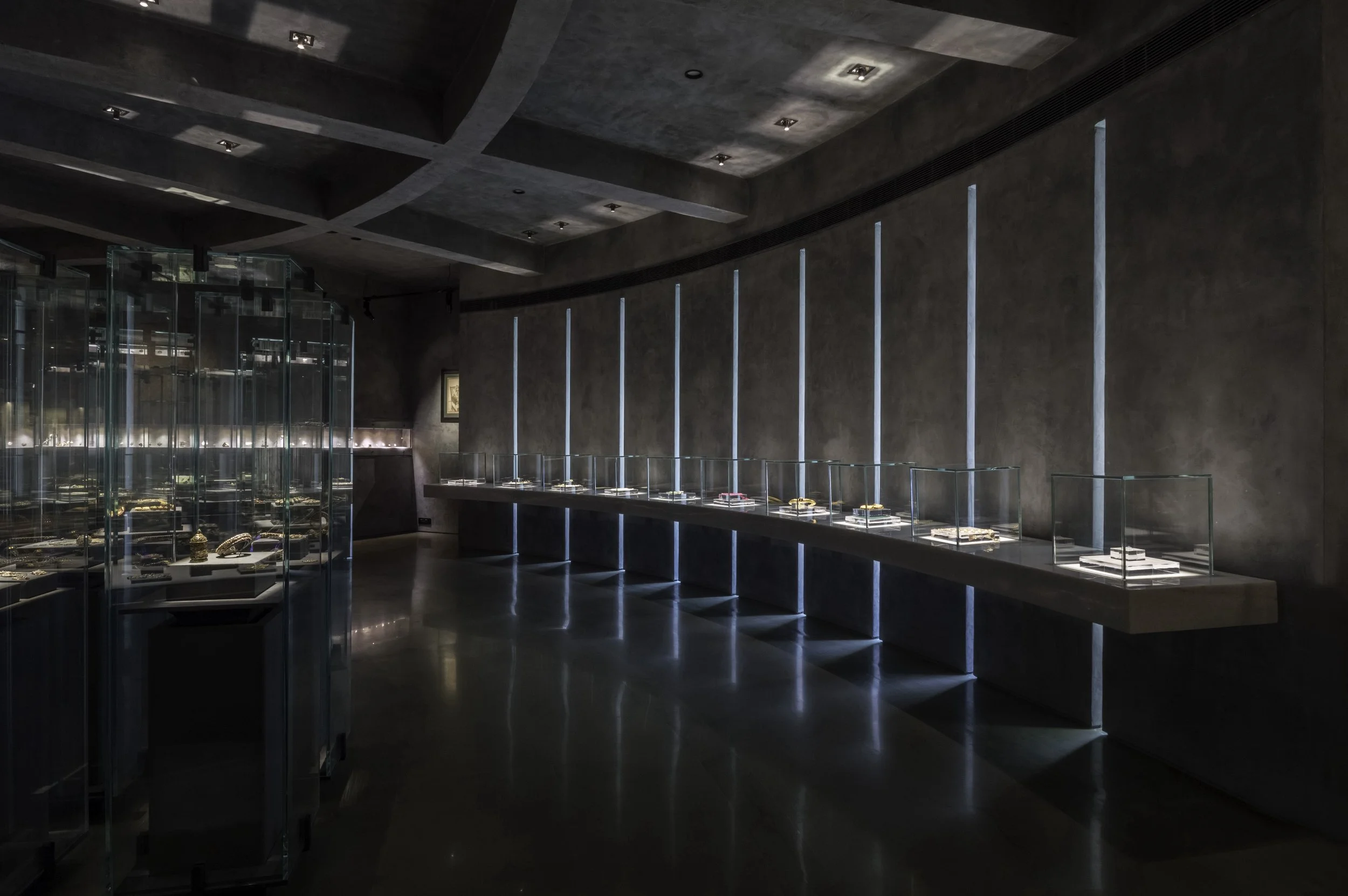 A gallery at Gyan Museum: vitrines lit from within along a dark, high-ceilinged room.